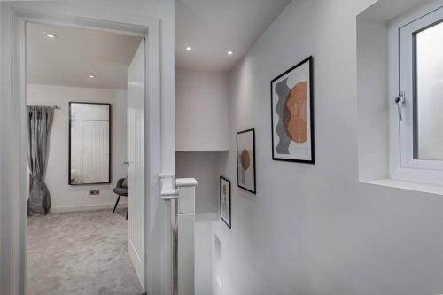 a white hallway with pictures on the wall at Prime Location, Modern 2br House in Sheffield