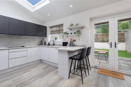 a kitchen with white cabinets and a counter with stools at Prime Location, Modern 2BR House in Sheffield