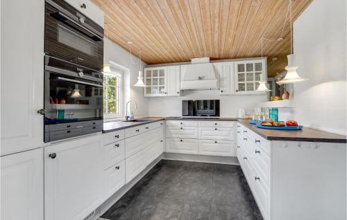 a kitchen with white cabinets and a wooden ceiling at Beautiful Home In Ulfborg With Wifi in Husby