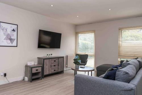 a living room with a couch and a flat screen tv at 3 BR Bungalow close to Peak District with Garden in Sheffield