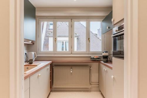 une cuisine avec une grande fenêtre et un radiateur dans l'établissement Le Petit Batelier - Strasbourg - Vue cathédrale, à Strasbourg