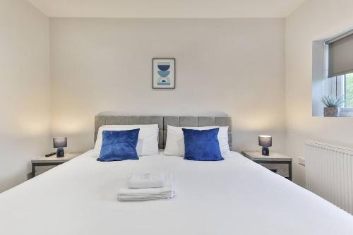 a bedroom with a large white bed with blue pillows at 3 Bed Refurbished, Modern House, Wifi, Patio Area in Sheffield