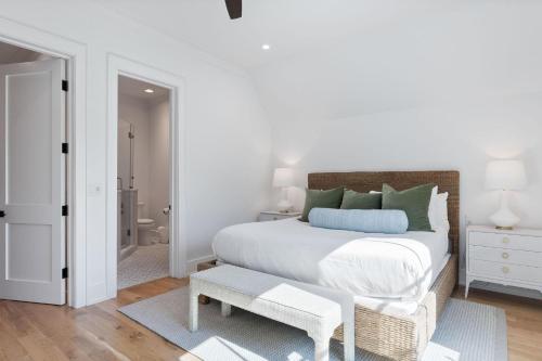 a white bedroom with a bed with a bench next to it at Shore To Have Fun in Seagrove Beach