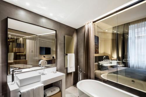 a bathroom with two sinks and a tub and a mirror at BoHo Prague Hotel - Small Luxury Hotels in Prague