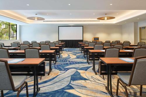 a conference room with tables and chairs and a screen at OUTRIGGER Waikiki Paradise Hotel in Honolulu