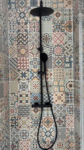 La salle de bains est pourvue d'un mur en carrelage avec un objet noir. dans l'établissement Casa Cubana, à Roubaix