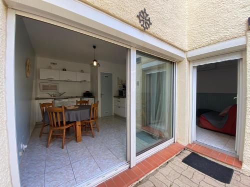 - une porte coulissante en verre sur une terrasse avec une table et des chaises dans l'établissement T2 terrasse, calme, proche mer et commodités, au Barcarès