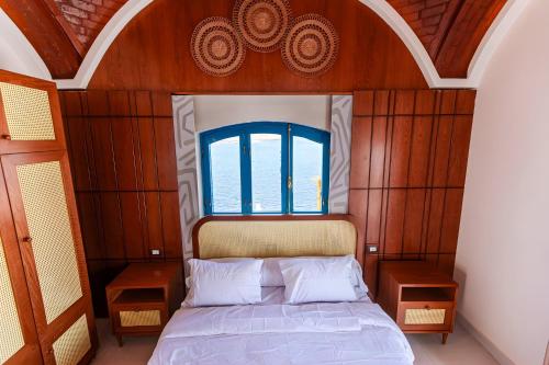 a bedroom with a bed with a wooden headboard and a window at Aro Kato Nubian Guest House in Aswan