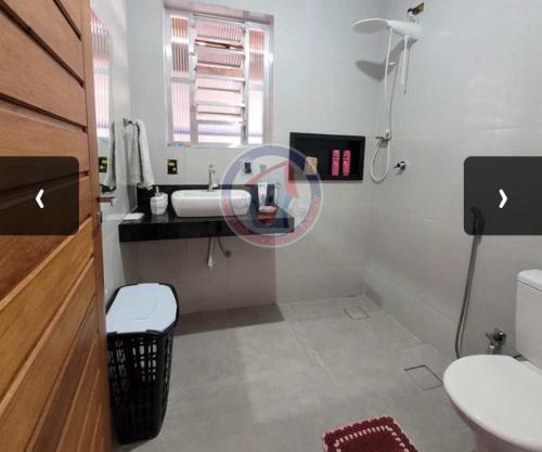 a bathroom with a sink and a toilet and a window at Casa em Mongaguá in Mongaguá