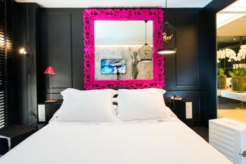 a bedroom with a large bed with a pink framed mirror at Hotel Mirador de Chamartín in Madrid