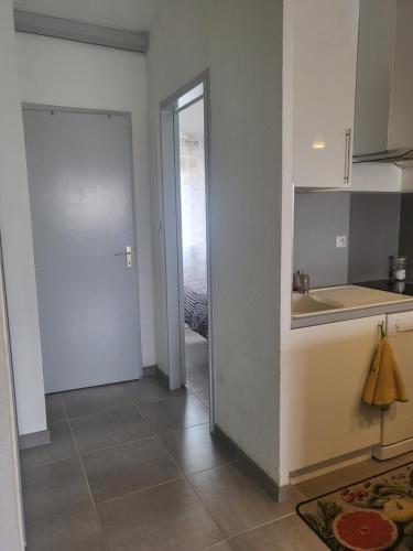- une cuisine avec un évier et une porte menant à une chambre dans l'établissement Bel appartement à 300 mètres de la plage +parking, à Valras-Plage