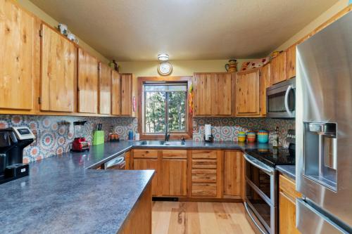 a kitchen with wooden cabinets and a sink and a window at Multiple Decks, Solarium Sitting Room, Dog Friendly, Office Space in Woodland Park