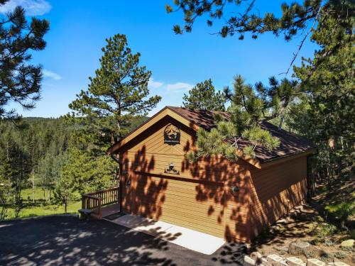 a house with a garage in the woods at Multiple Decks, Solarium Sitting Room, Dog Friendly, Office Space in Woodland Park