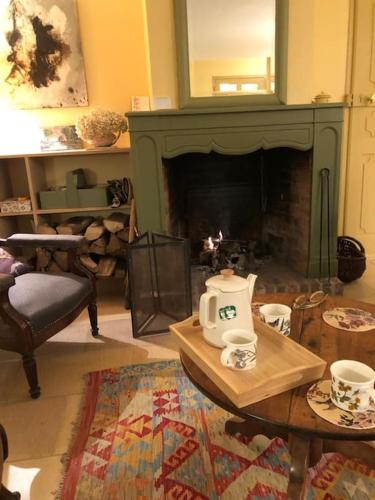 - un salon avec une cheminée et une table avec une théière dans l'établissement Nouveau - Le Bois d'Hautôt, à Hautot-sur-Mer