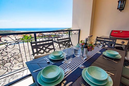 a table with plates and wine glasses on a balcony at Cabo Cottage Copala · Stunning * Luxury Ocean View 2BR*Resort Living in Cabo San Lucas