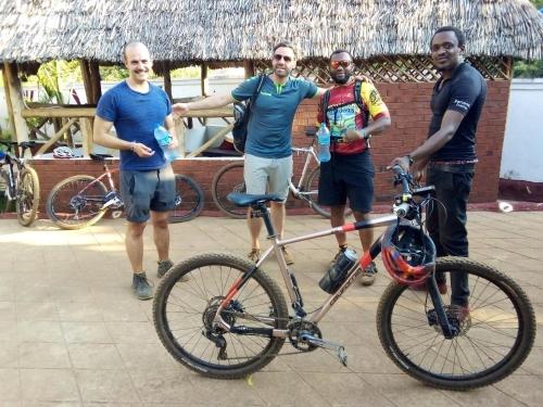 a group of men standing next to a bike at Moshi hostel lodge in Msaranga