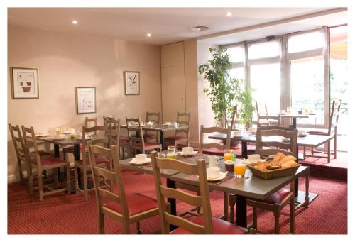 a dining room with tables and chairs and windows at Kyriad Villefranche Sur Saone in Villefranche-sur-Saône