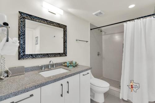 a bathroom with a sink and a toilet and a mirror at Bahia Mar-Solare Tower, Beachfront Resort with Two Pools in South Padre Island