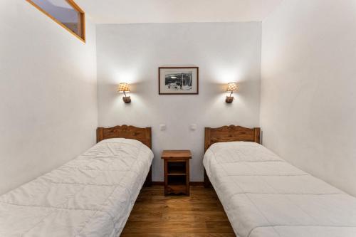 deux lits dans une chambre aux murs blancs dans l'établissement Résidence Les Hauts De Preclaux - Appartement spacieux au coeur des Orres MAE-5321, aux Orres