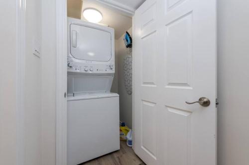 małą białą kuchnię z pralką i suszarką w obiekcie Modern & Cozy 1 Bedroom with fast Wi-Fi, BBQ & Patio w mieście Barrie