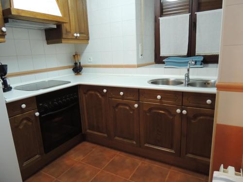 a kitchen with wooden cabinets and a sink at El Encinar in Tarilonte