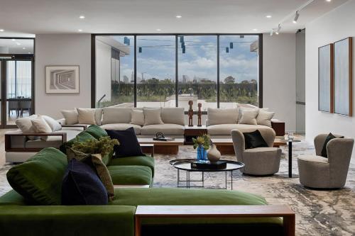 a living room with a green couch and chairs at Caulfield Apartments by Urban Rest in Melbourne