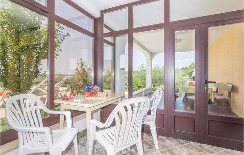 a dining room with white chairs and a table and windows at Awesome Home In Meloni With Sauna in Karojba