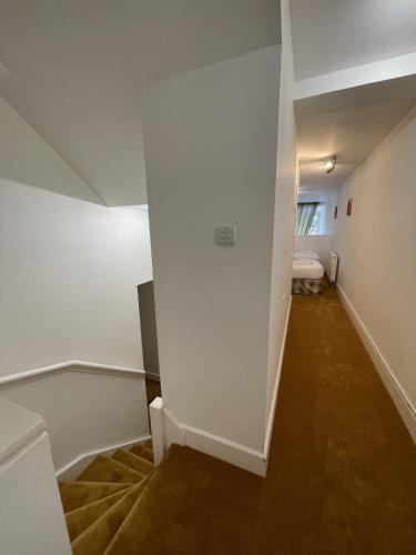 a hallway with white walls and a bed in a room at The Classrooms, Loch Ness Abbey - 142m2 Lifestyle & Heritage apartment - Pool & Spa - The Highland Club - Resort on lake shores in Fort Augustus