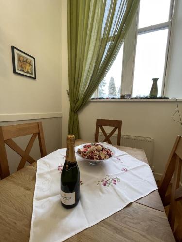 a bottle of wine and a bowl of flowers on a table at The Classrooms, Loch Ness Abbey - 142m2 Lifestyle & Heritage apartment - Pool & Spa - The Highland Club - Resort on lake shores in Fort Augustus