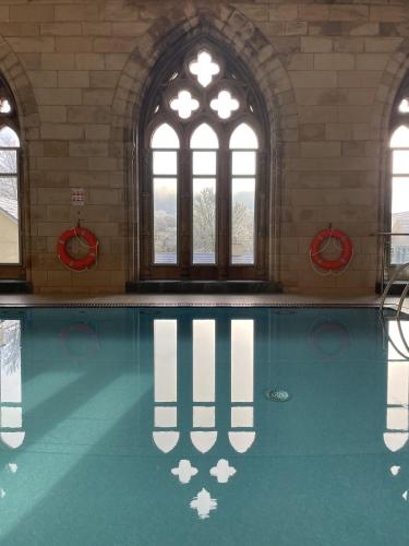 a swimming pool in a building with windows at The Classrooms, Loch Ness Abbey - 142m2 Lifestyle & Heritage apartment - Pool & Spa - The Highland Club - Resort on lake shores in Fort Augustus
