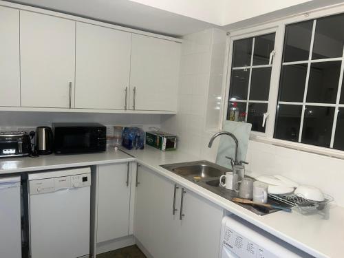 a white kitchen with a sink and a microwave at The Coral Guest House 1 Mile from Winchester Market in Winchester
