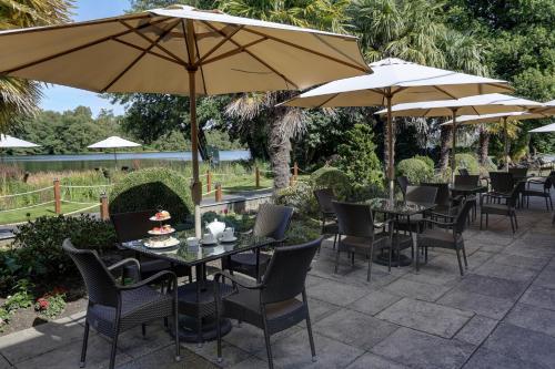 a patio with tables and chairs and umbrellas at Frensham Pond Country House Hotel & Spa in Farnham