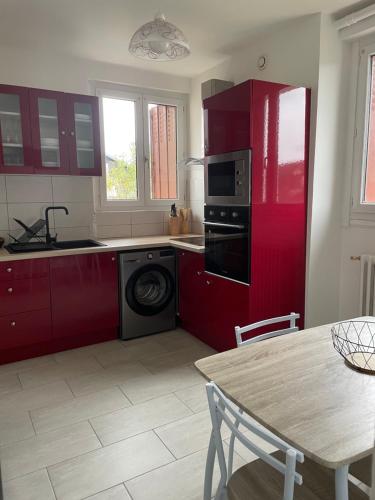 - une cuisine avec des placards rouges et un lave-linge dans l'établissement Le gîte de Myrlène-30min Parc Fédéral-12min CNPE CAUTION OBLIGATOIRE SWIKLY, à Sully-sur-Loire