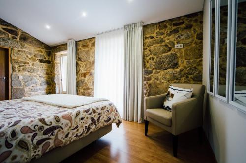 a bedroom with a bed and a chair at Vougaldeias Casas da Seara in Sever do Vouga