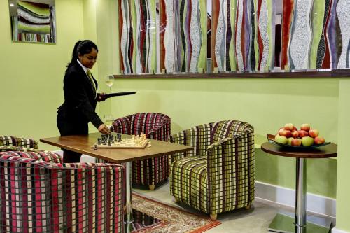 a woman in a room with a table and chairs at Frensham Pond Country House Hotel & Spa in Farnham
