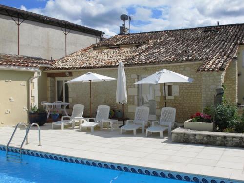 a pool with chairs and umbrellas next to a house at Maison Du Ruisseau in Malaville