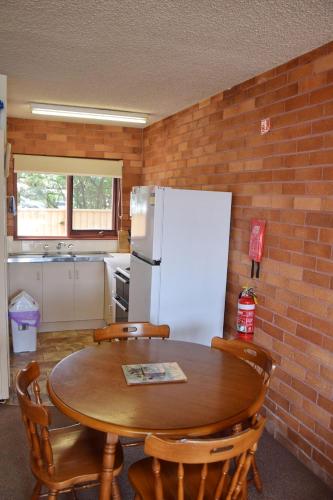a kitchen with a table and a white refrigerator at Anglers Lodge 4 - bring your own linen in South West Rocks