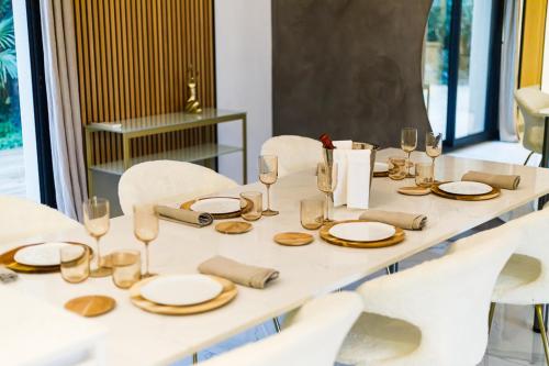 a white table with plates and glasses on it at Villa Meyzieu Grand Large in Meyzieu