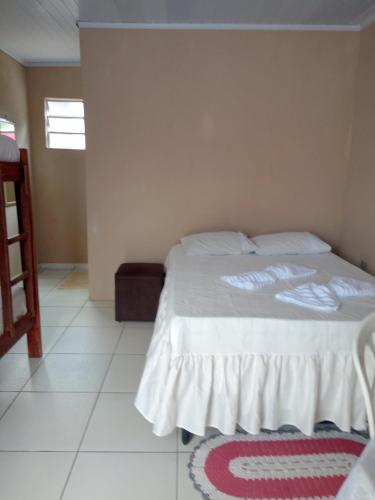 a bedroom with a bed with white sheets and a window at Pousada Recanto da Villa in Mucugê