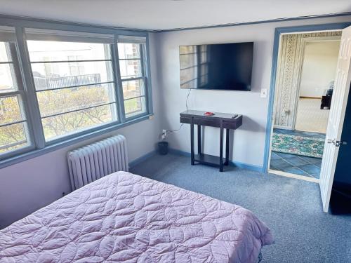WatchungにあるCozy & Stylish Studio with Beautiful Lake Views & Fast Wifiのベッドとテーブルとテレビのある寝室