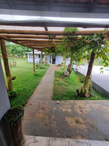 a wooden pergola with a bench in a park at Chácara Cantinho dos Sonhos in Chapada dos Guimarães