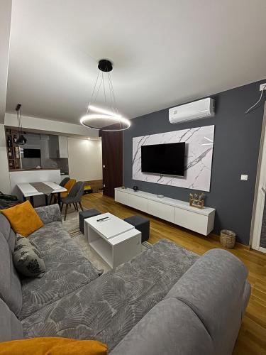 a living room with a couch and a tv on a wall at Luxury Apartment in Aerodrom in Skopje