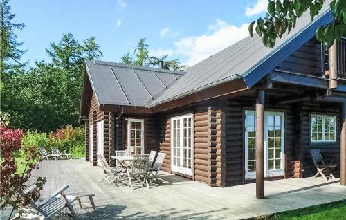 a log cabin with a table and chairs on a deck at Holiday Home Katholm in Ålsrode