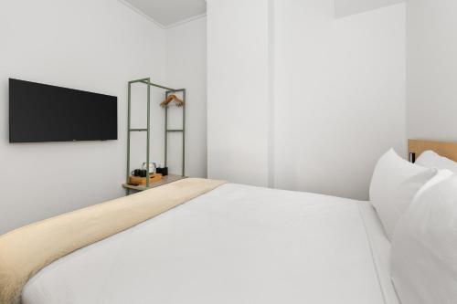 a bedroom with a white bed and a flat screen tv at YHA Brisbane City in Brisbane