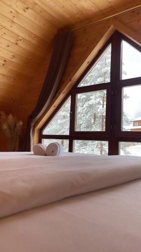 a bed in a room with a large window at Pino House Zlatibor-Tornik in Ribnica