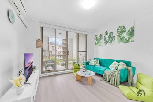 a living room with a green couch and a tv at Utopia 2B2B in Wentworth Point&Olympic Park in Sydney