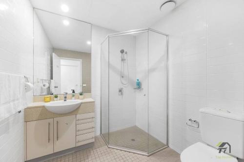 a white bathroom with a shower and a sink at Utopia 2B2B in Wentworth Point&Olympic Park in Sydney