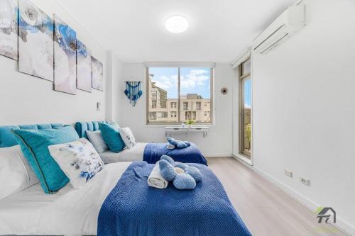 a bedroom with blue and white furniture and a window at Utopia 2B2B in Wentworth Point&Olympic Park in Sydney