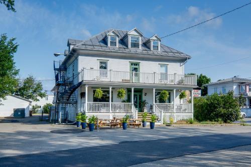 a white house with a porch and tables on the street at Chambre 305 de l'hôtel Victoria confortable et moderne in Saint-Pascal
