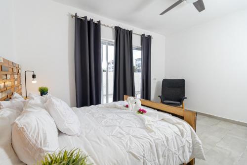 a bedroom with a large white bed and a chair at Coastal Luxury 2-Bed w Pool Access in Bayahibe in Bayahibe
